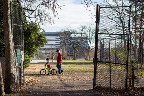 A man watches a child ride a bike on the first day of winter (Flickr pool photo by Ddimick)