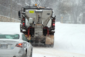 A salt truck drives on N. Park Drive with its plow up