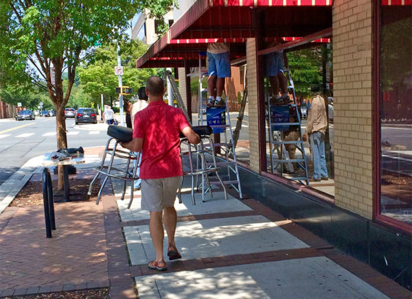 A man carries barstools away from Hard Times Cafe in Clarendon while workers remove the awnings